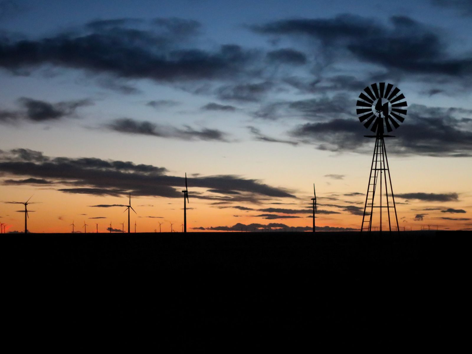 Windmill silhouetted against a purple desert sunset