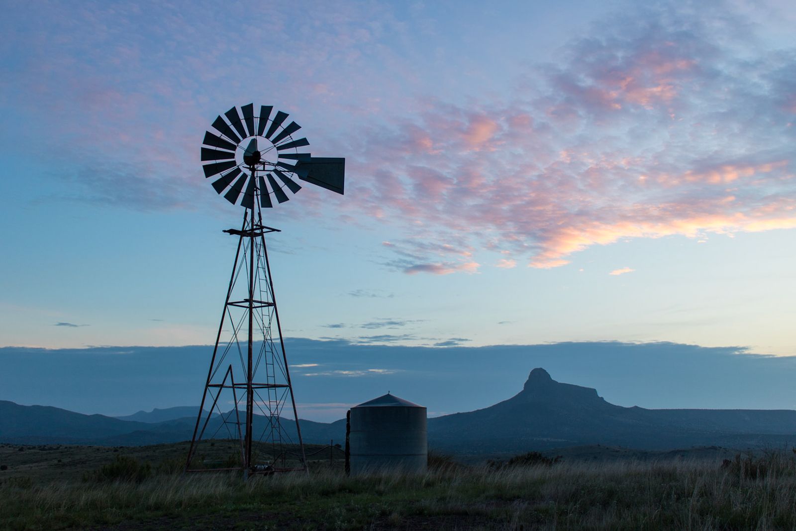 Windmill and outbuilding under pink clouds at dawn