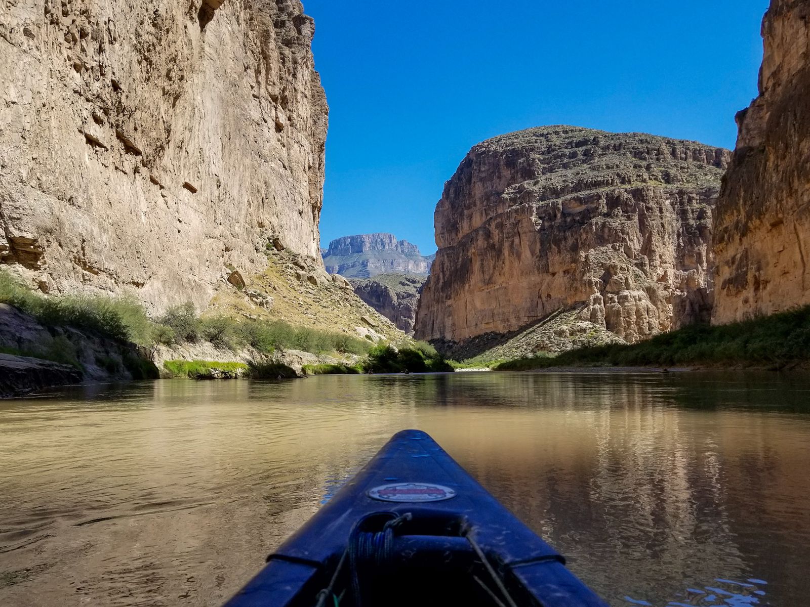 View downriver from a kayak toward canyon walls
