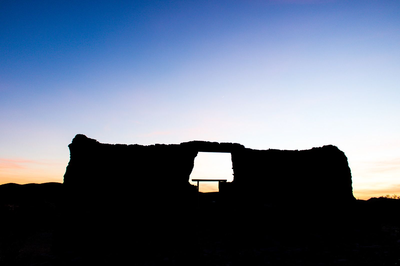 Lamp glowing inside a rock silhouette at blue hour
