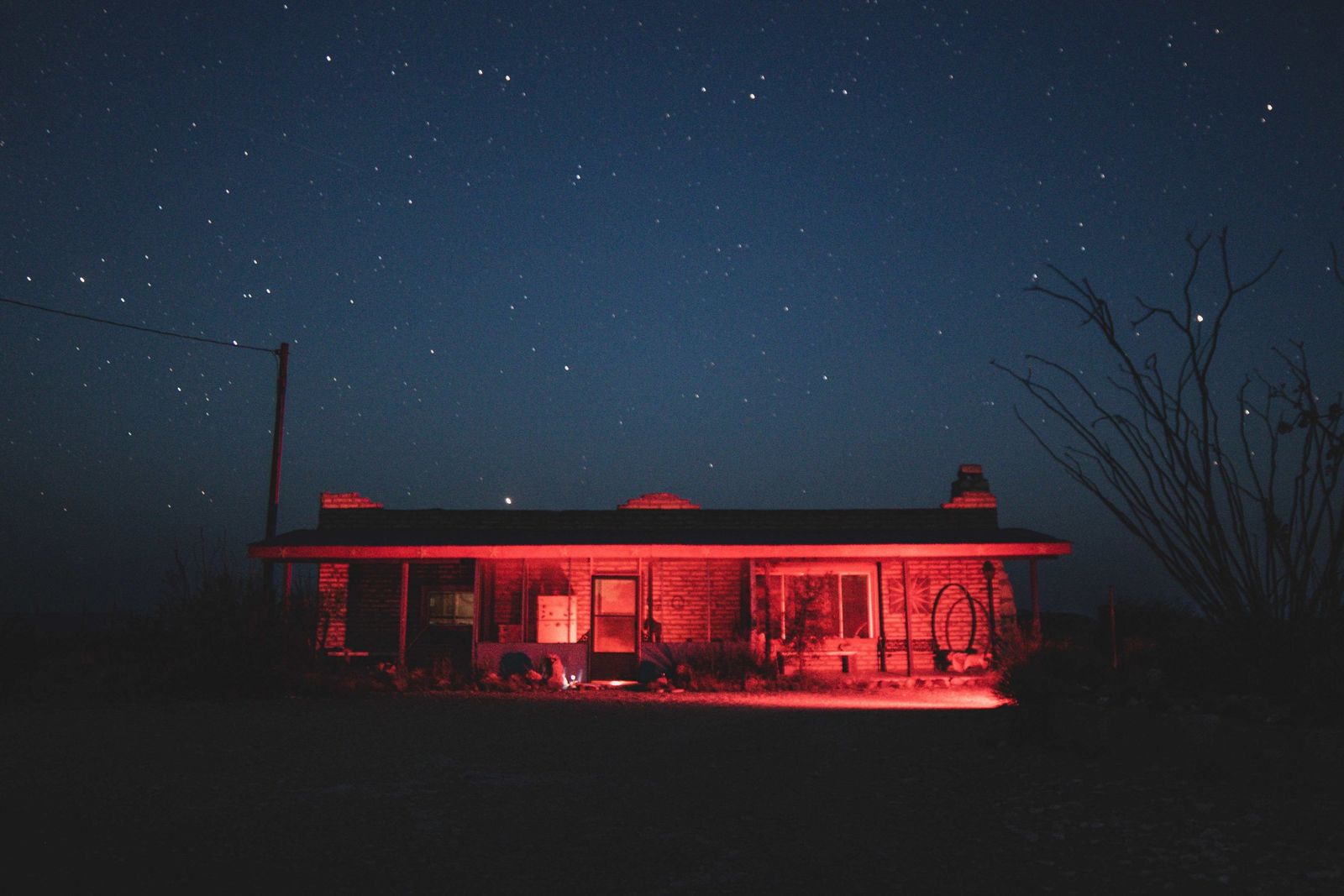 Roadside building lit red under a starry desert sky